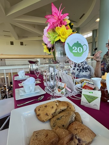 Scones, tablewear, a floral centerpiece, and a table marker with a green teapot.