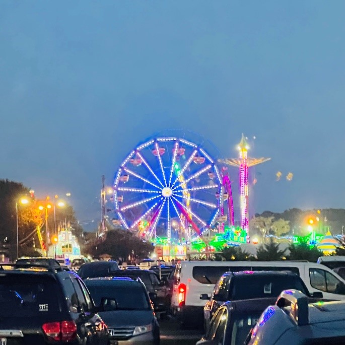 Evening view of the Wilson County Fair from the parking area, with the rides bright with lights