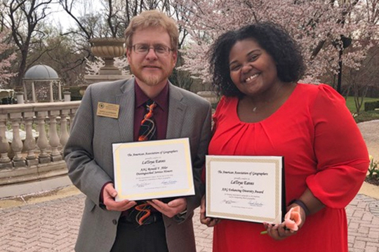 Dr. LaToya Eaves, right, an assistant professor in Global Studies and Human Geography at MTSU, and Dr. Derek Alderman, current past president of the American Association of Geographers, hold the two award certificates Eaves received at the association’s luncheon earlier this spring in Washington, D.C. (Submitted photo)