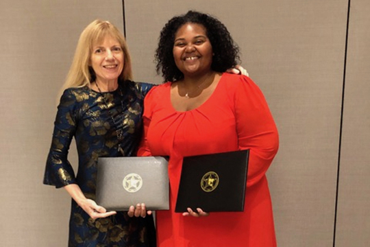 Dr. LaToya Eaves, right, an assistant professor in Global Studies and Human Geography at MTSU, is pictured with Dr. Sheryl Luzzadder-Beach, president of the American Association of Geographers, at the association’s luncheon earlier this spring in Washington, D.C. Eaves holds the two award certificates she received for the Ronald F. Abler Distinguished Service Honors award and the AAG Enhancing Diversity Award. (Submitted photo)