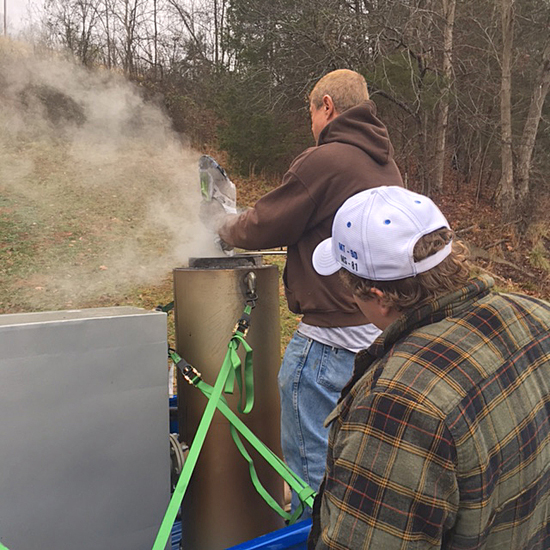 MTSU senior Colton Huckabee, front, observes as Terry Young makes adjustments to the wood gasification unit during the 131-mile research run made by retiring professor Cliff Ricketts.