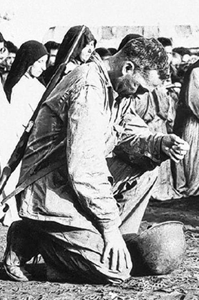 Marine Capt. John N. Popham takes time out from the fierce Saipan fighting to kneel in prayer at Catholic services held for native Chamorros at a Marine Civil Affairs Internment Camp on July 22, 1944. (Photo courtesy of Associated Press/Chattanooga Times Free Press)