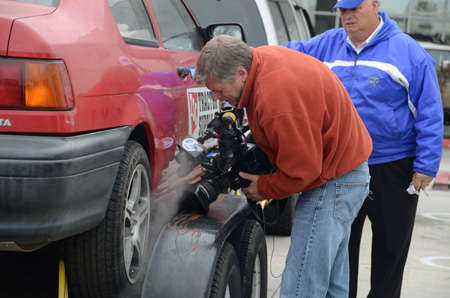 As MTSU professor Cliff Ricketts, right, observes, Los Angeles KABC TV 7 photojournalist Jim Brown films the steam that comes out of the tailpipe on the 1994 Toyota Tercel, one of two vehicles used in the 2,600-mile coast-to-coast trip. MTSU's team spent about two hours after Toyota of Huntington Beach extended the invitation to Ricketts. (MTSU photo by Randy Weiler)