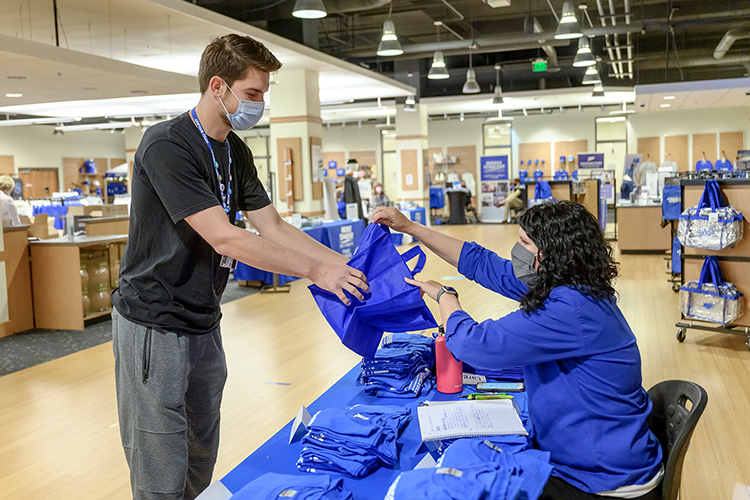 Ginger Corley, right, MTSU alumni relations director, helps graduating senior Nathan L. Smith of Unionville, Tennessee, with a bag for his cap, gown and other commencement items in Phillips Bookstore Monday, May 3. Smith, a biochemistry major whose undergrad research includes food safety and mosquito-borne diseases, plans to attend medical school after he receives his bachelor's degree in Murphy Center Saturday afternoon, May 8. MTSU's spring 2021 graduates are returning to Murphy Center May 7-9 for the first time since 2019 for a three-day, 10-event, socially distanced commencement weekend. (MTSU photo by J. Intintoli)