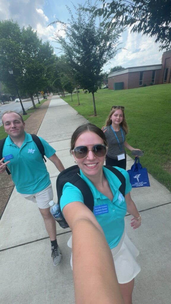 SOAs posing with a student walking on campus