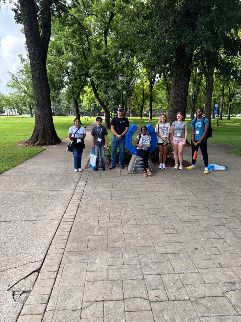 Students standing beside the blue horseshoe at Walnut Grove with their Student Orientation Assistant.