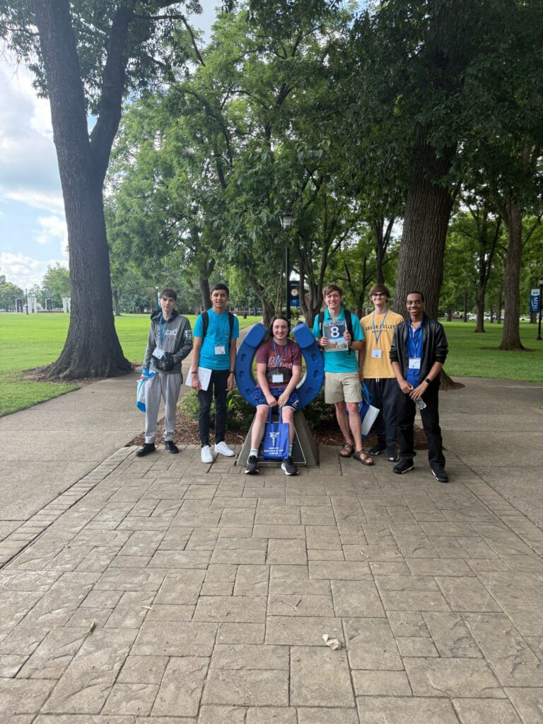 Students standing beside the blue horseshoe at Walnut Grove with their Student Orientation Assistant.
