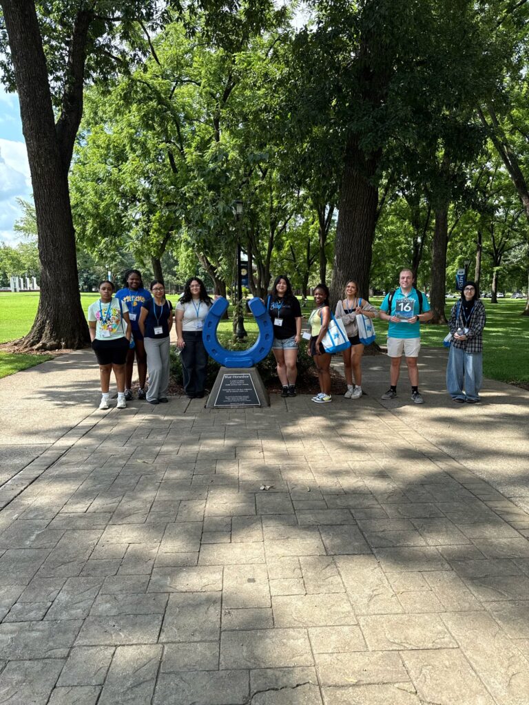 Students standing beside the blue horseshoe at Walnut Grove with their Student Orientation Assistant.
