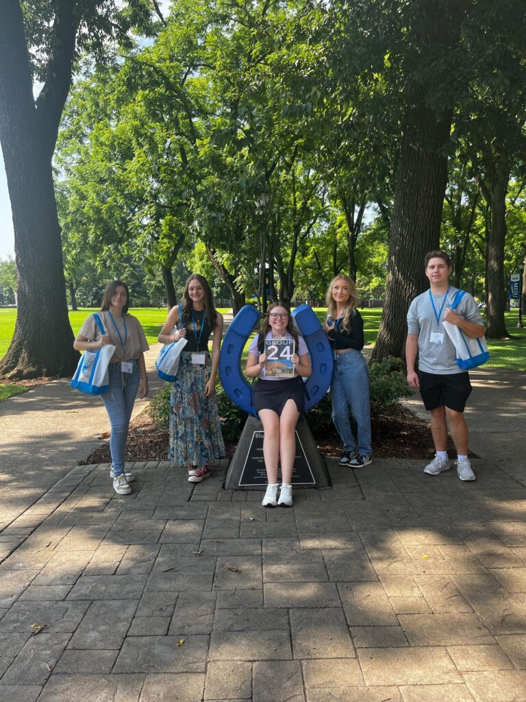 Students standing beside the blue horseshoe at Walnut Grove with their Student Orientation Assistant.