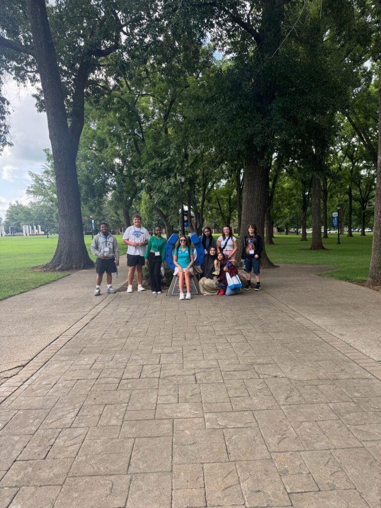 Students standing beside the blue horseshoe at Walnut Grove with their Student Orientation Assistant.
