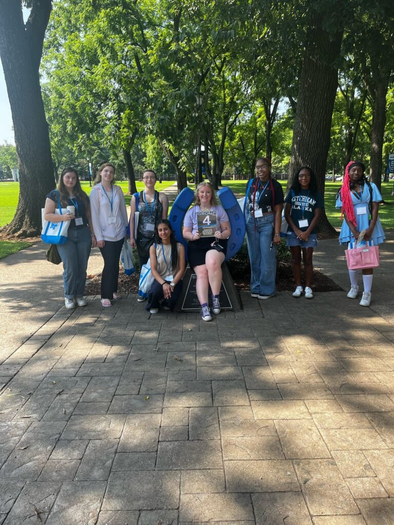 Students standing beside the blue horseshoe at Walnut Grove with their Student Orientation Assistant.