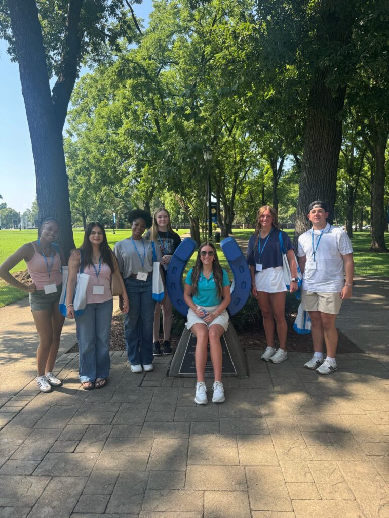 Students standing around the blue horseshoe in Walnut Grove with their Student Orientation Assistant.