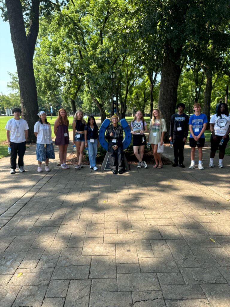 Students standing beside the blue horseshoe at Walnut Grove with their Student Orientation Assistant.