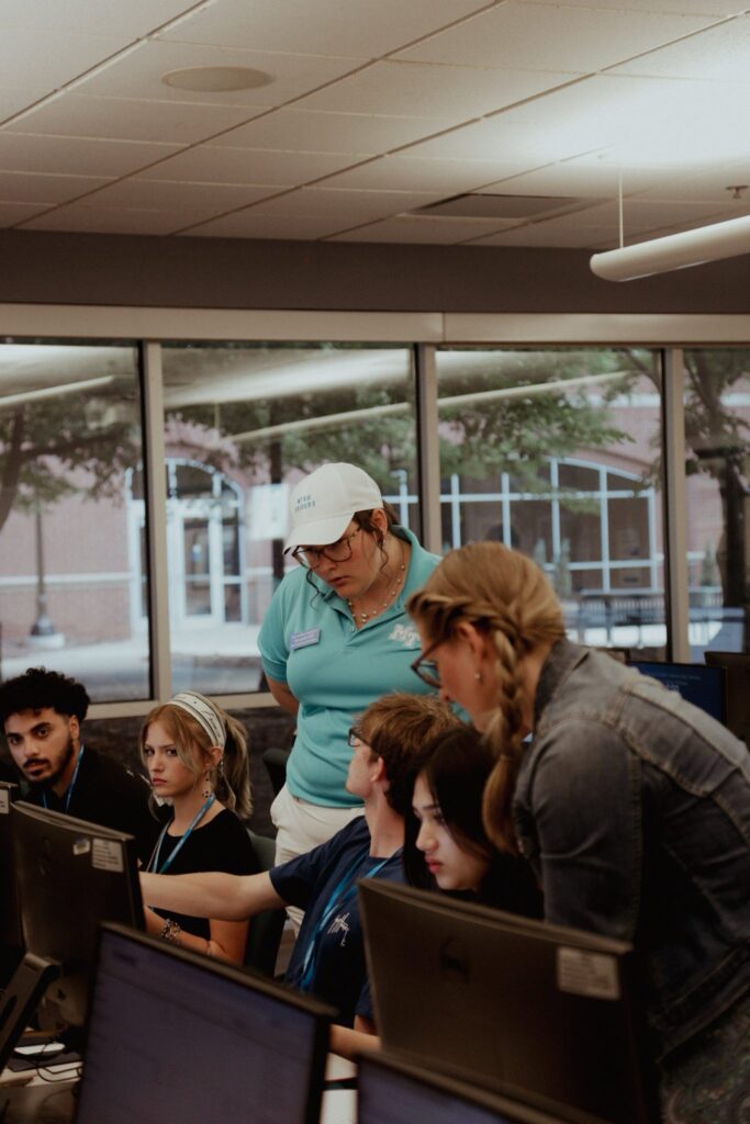Students sitting in a computer lab with a Student Orientation Assistant.