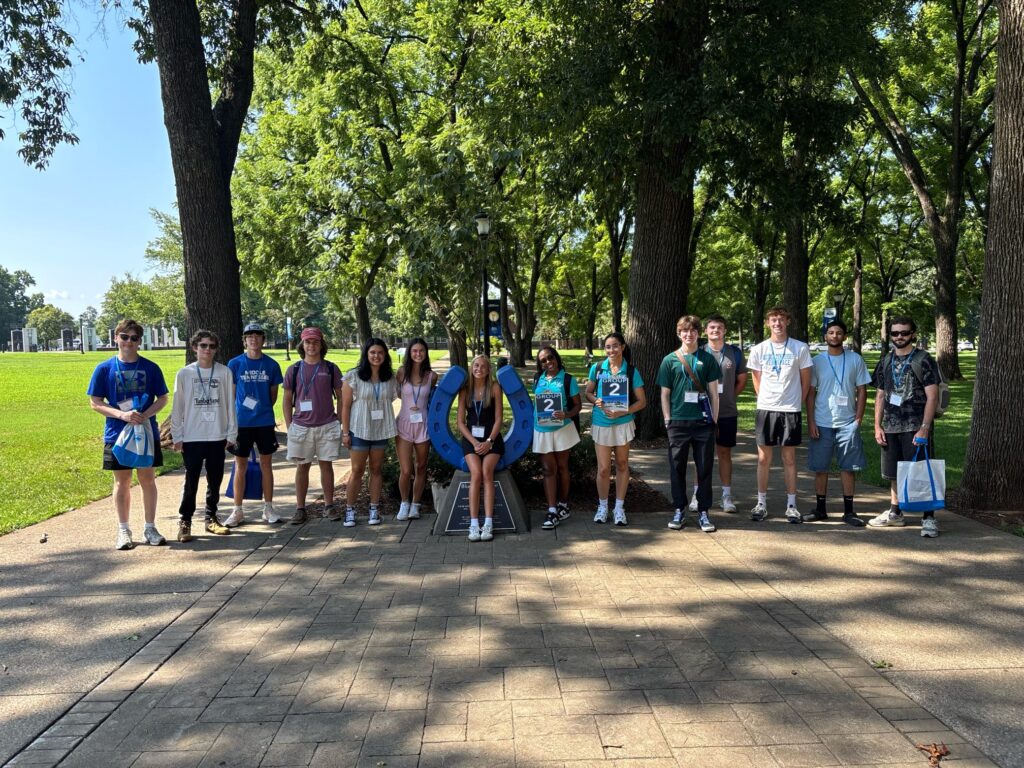 Students standing beside the blue horseshoe at Walnut Grove with their Student Orientation Assistant.