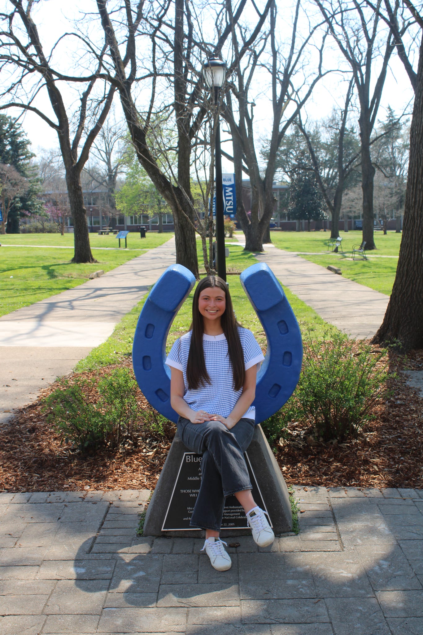 Photo of Amelia Steffy sitting on the blue horseshoe in Walnut Grove at MTSU.