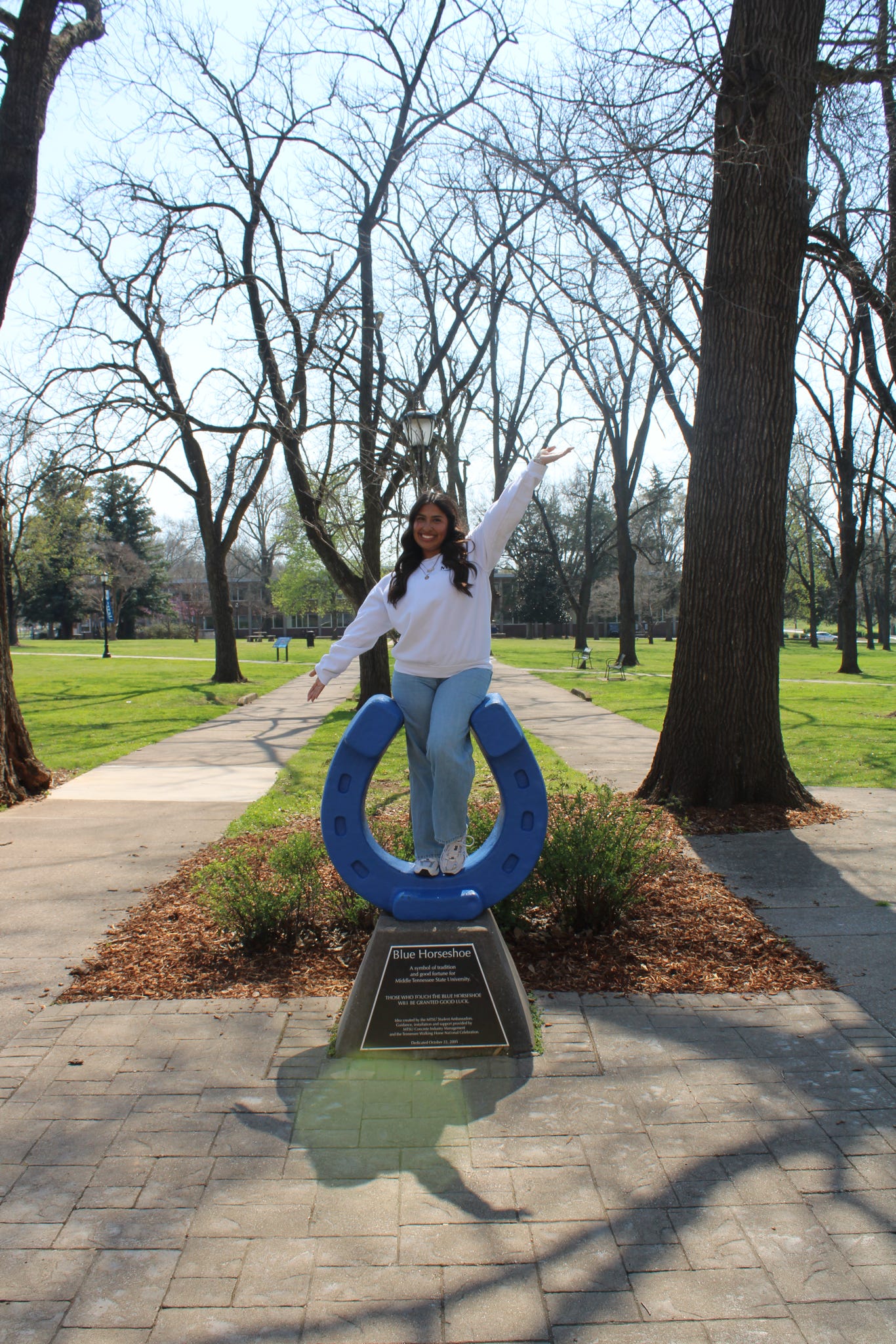 Photo of Athziry Barajas standing on top of the blue horseshoe in Walnut Grove at MTSU.