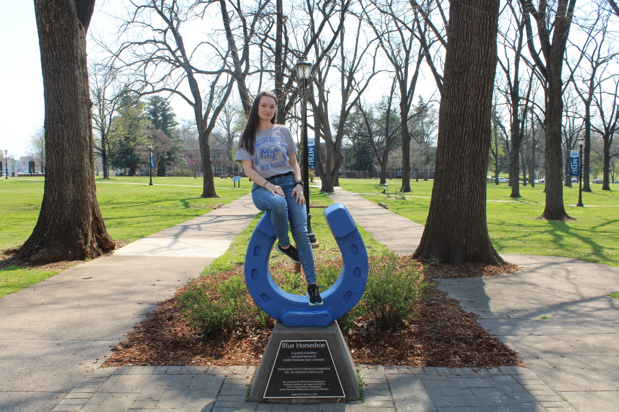 Photo of Autumn Cohee sitting on top of the blue horseshoe in Walnut Grove at MTSU.