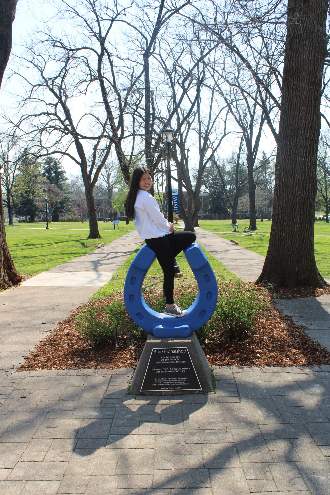 Photo of Avery McGiboney sitting on top of the blue horseshoe in Walnut Grove at MTSU.