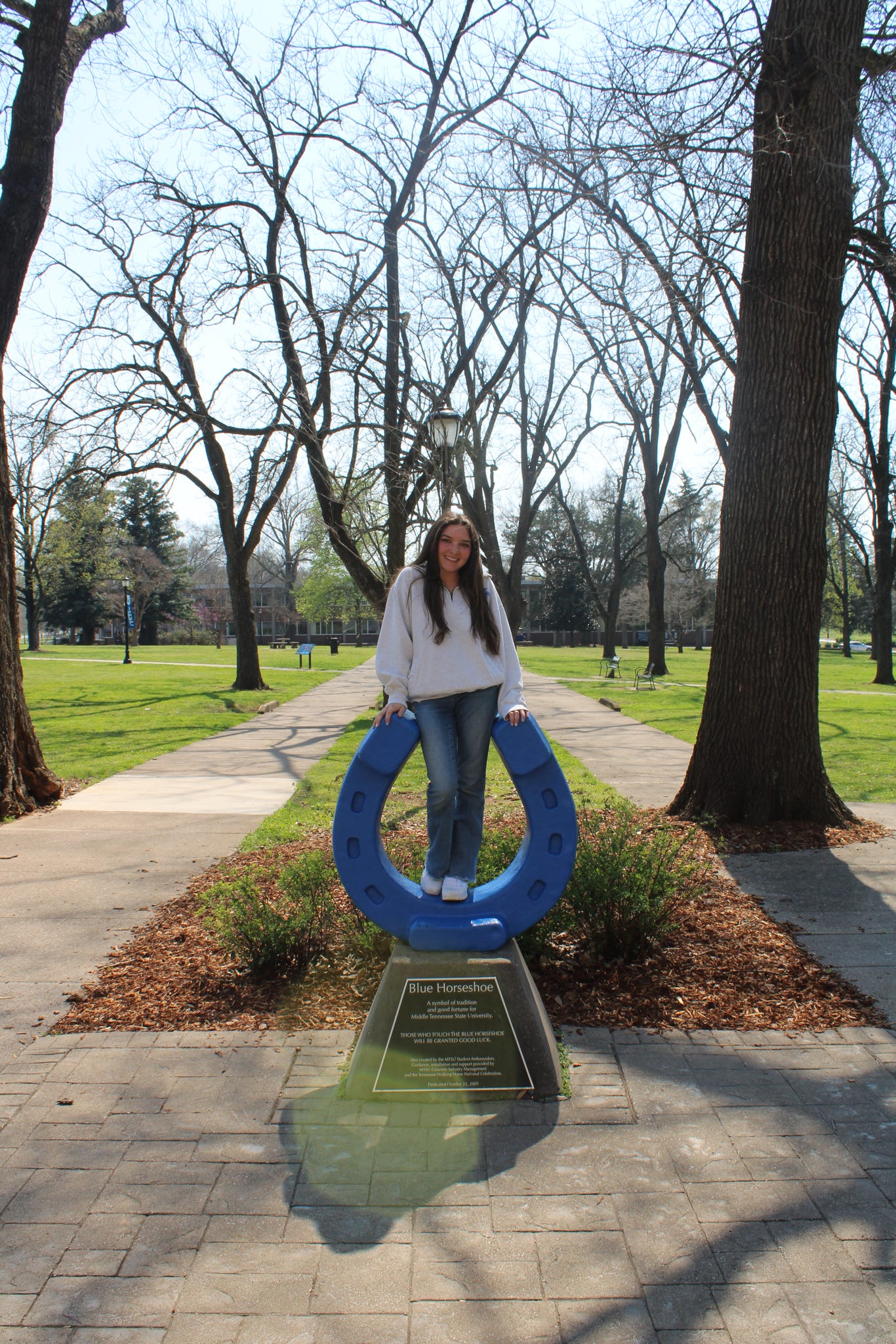 Photo of Bella DiMartino standing on top of the blue horseshoe in Walnut Grove at MTSU.