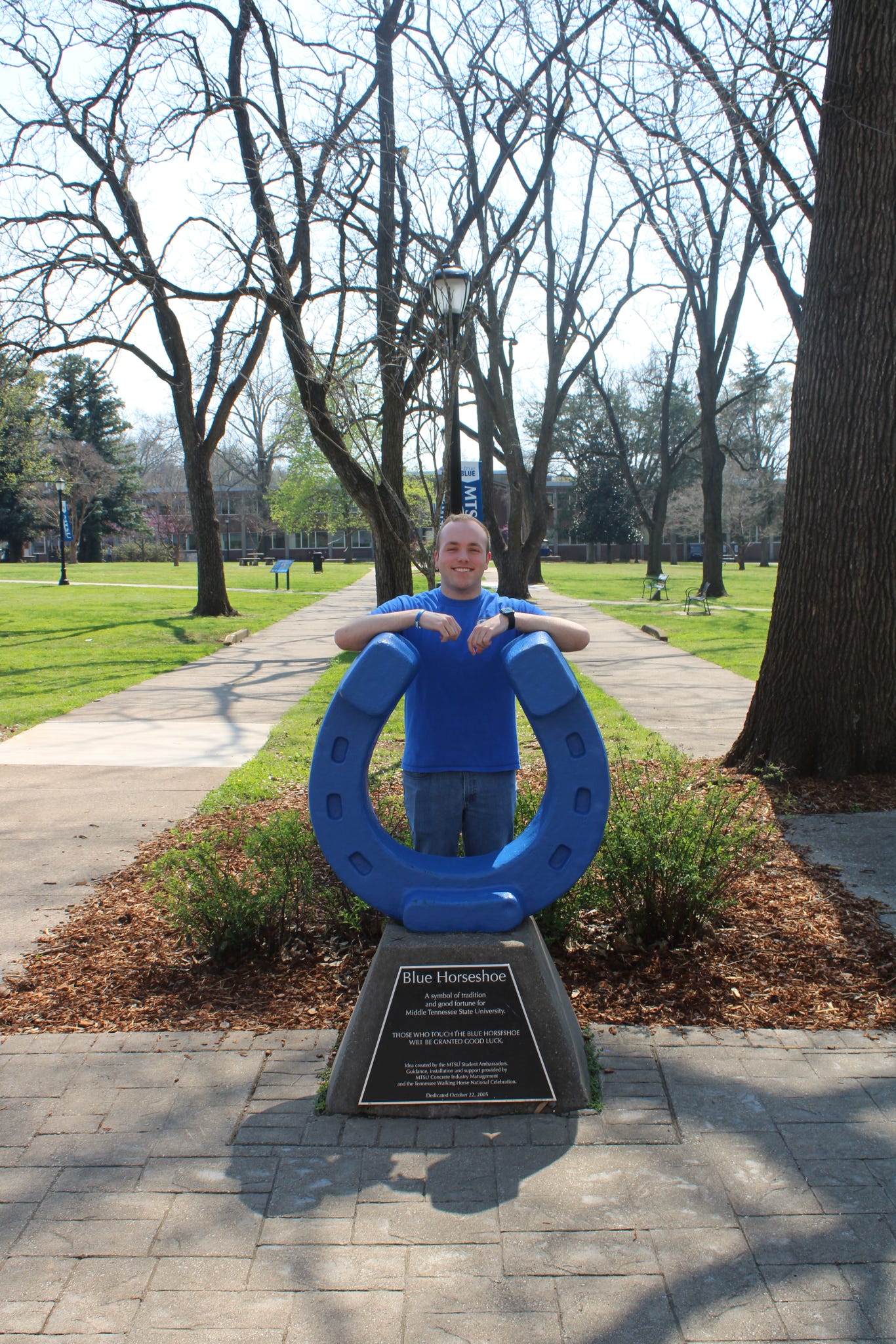 Photo of Cooper Jones standing behind the blue horseshoe in Walnut Grove at MTSU.