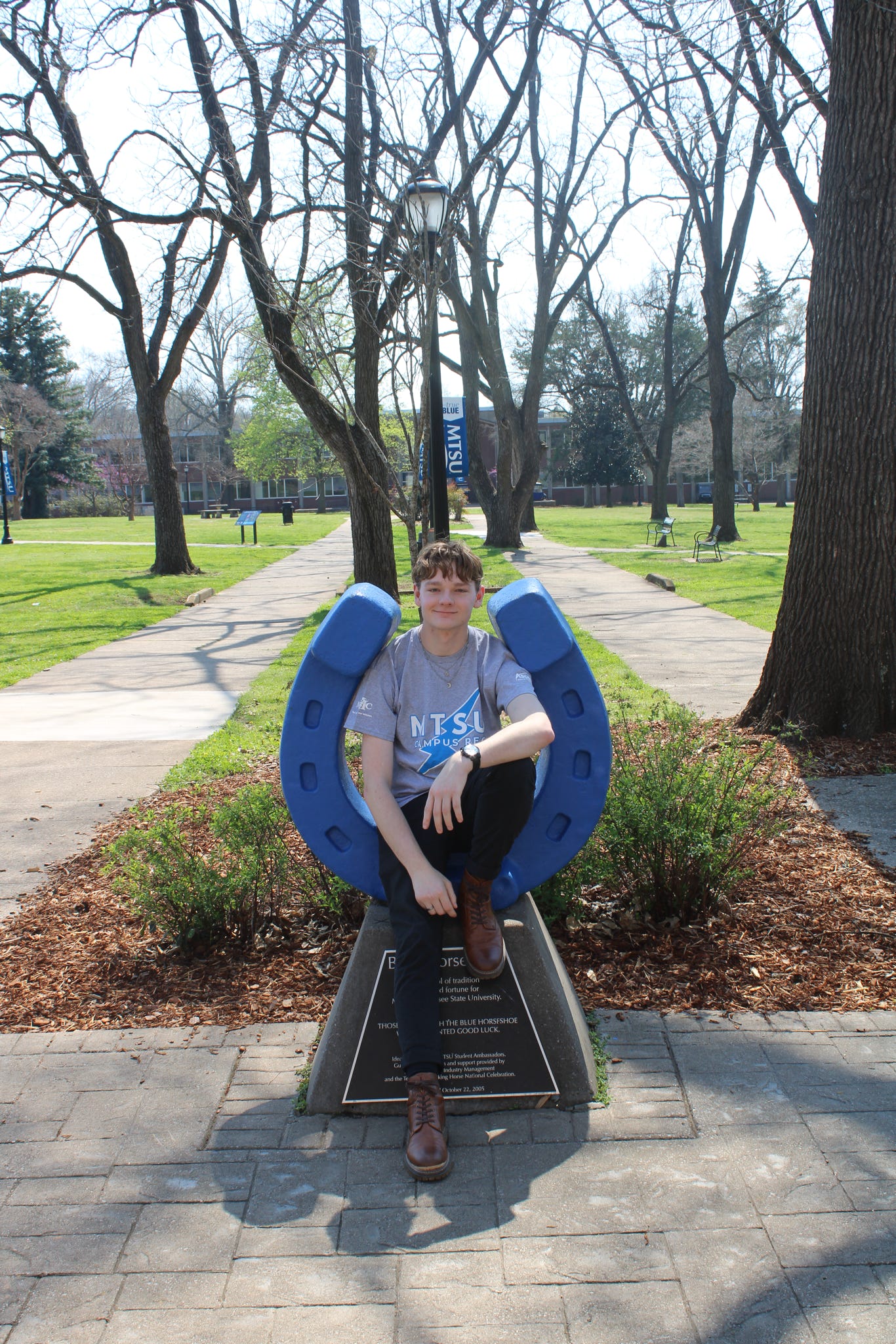 Photo of Edward Ozment sitting on the blue horseshoe in Walnut Grove at MTSU.