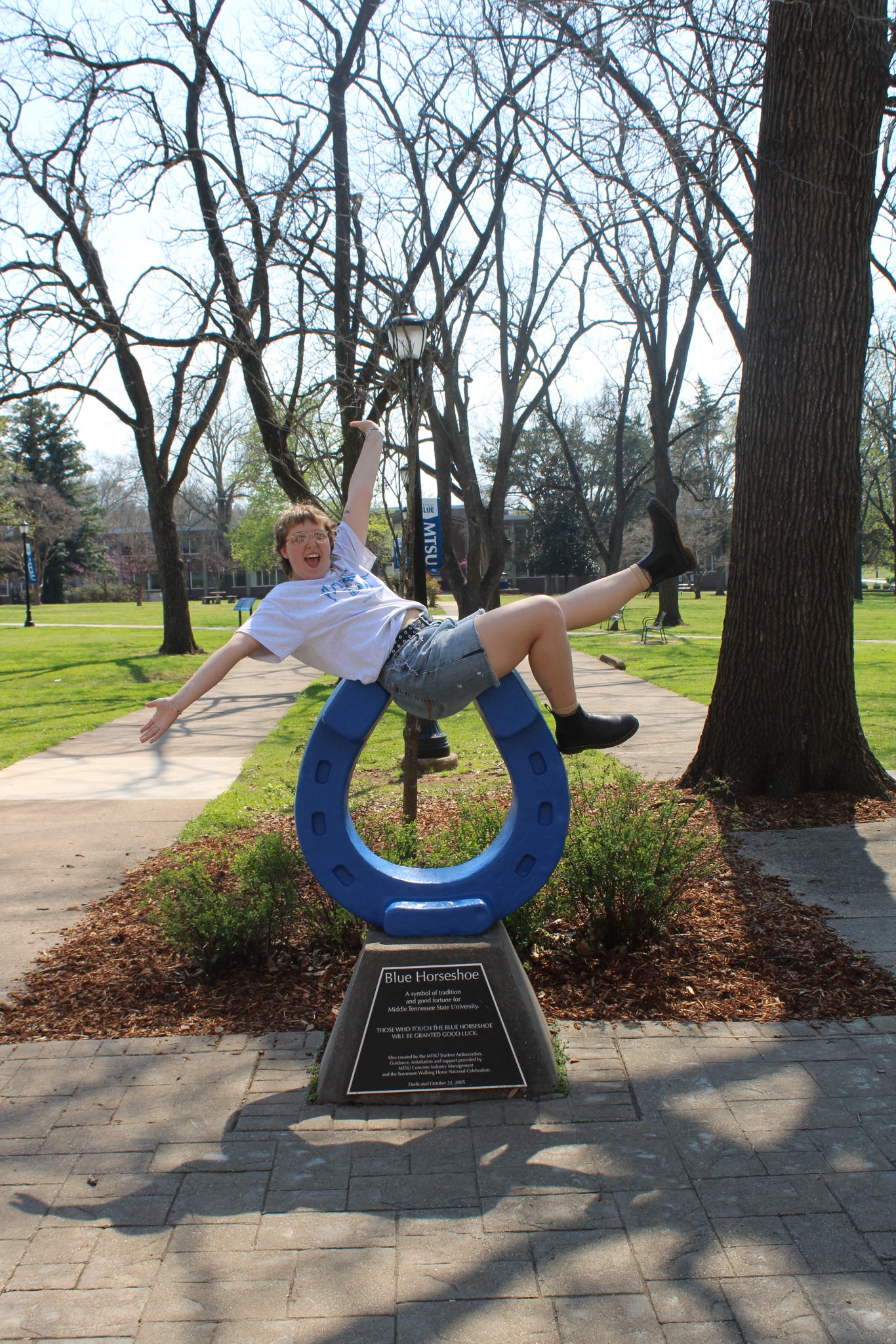 Photo of Erika Hill sitting on top of the blue horseshoe in Walnut Grove at MTSU.