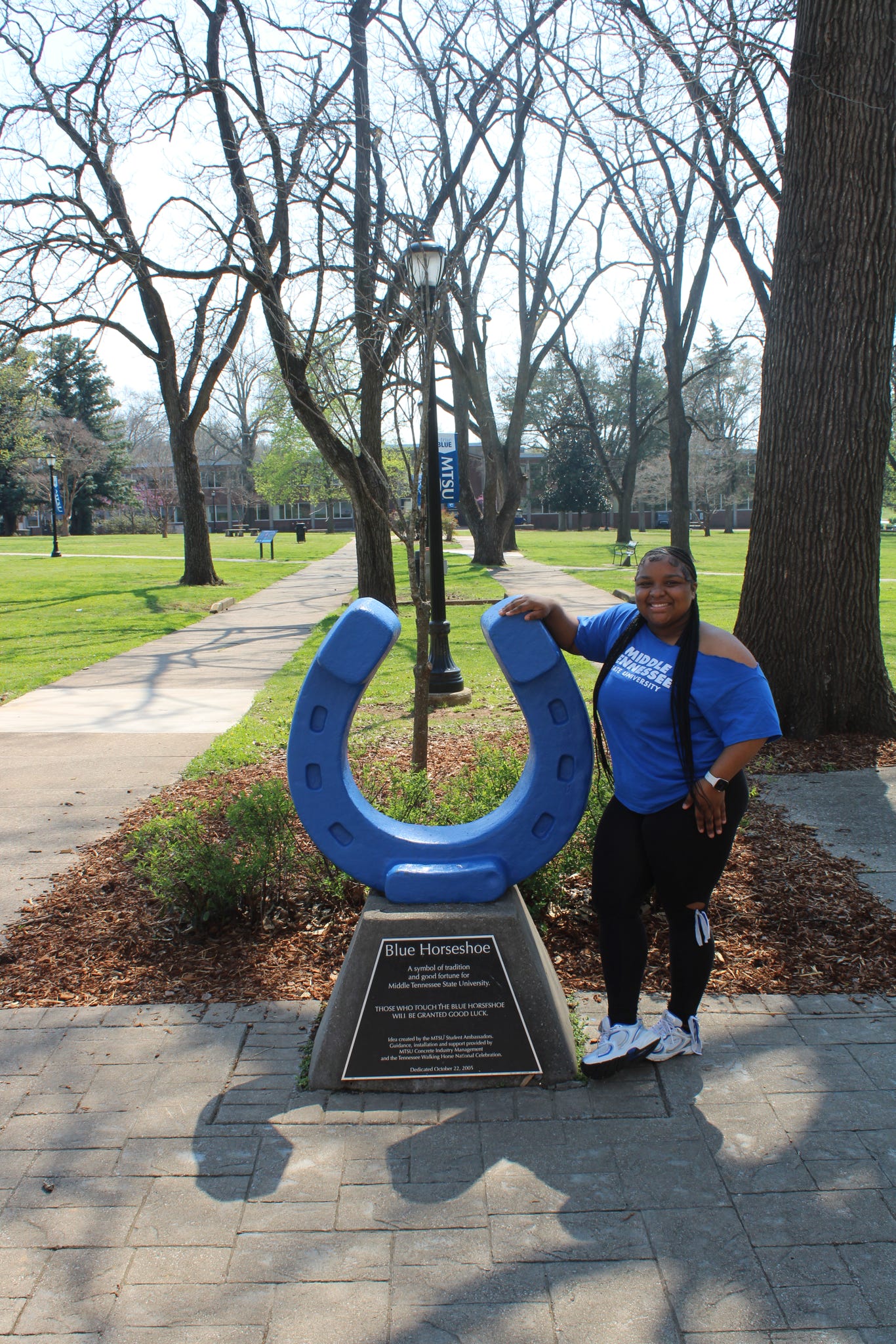 Photo of Ermya Bonds standing beside the blue horseshoe in Walnut Grove at MTSU.