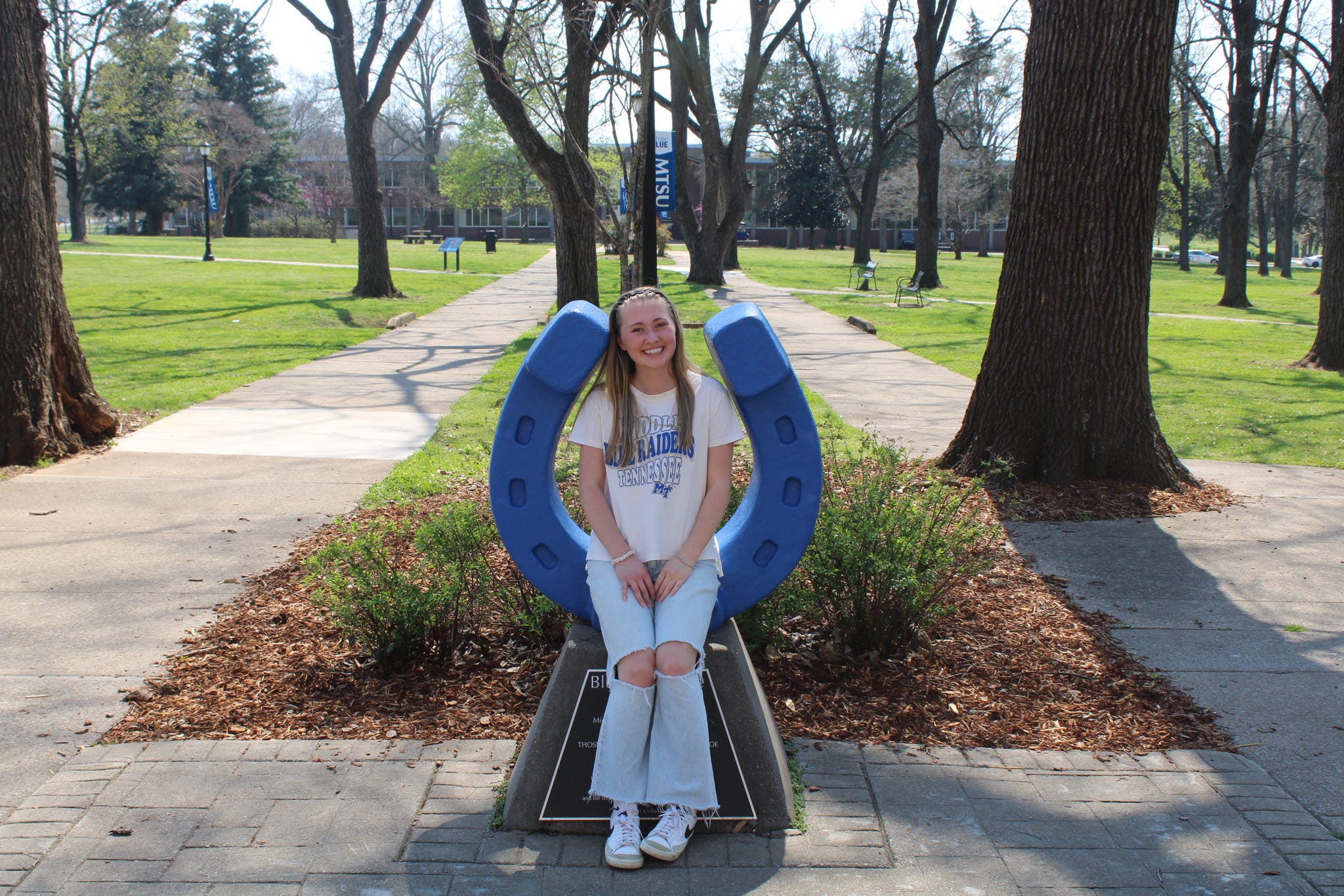 Photo of Gracie Campbell sitting on the blue horseshoe in Walnut Grove at MTSU.