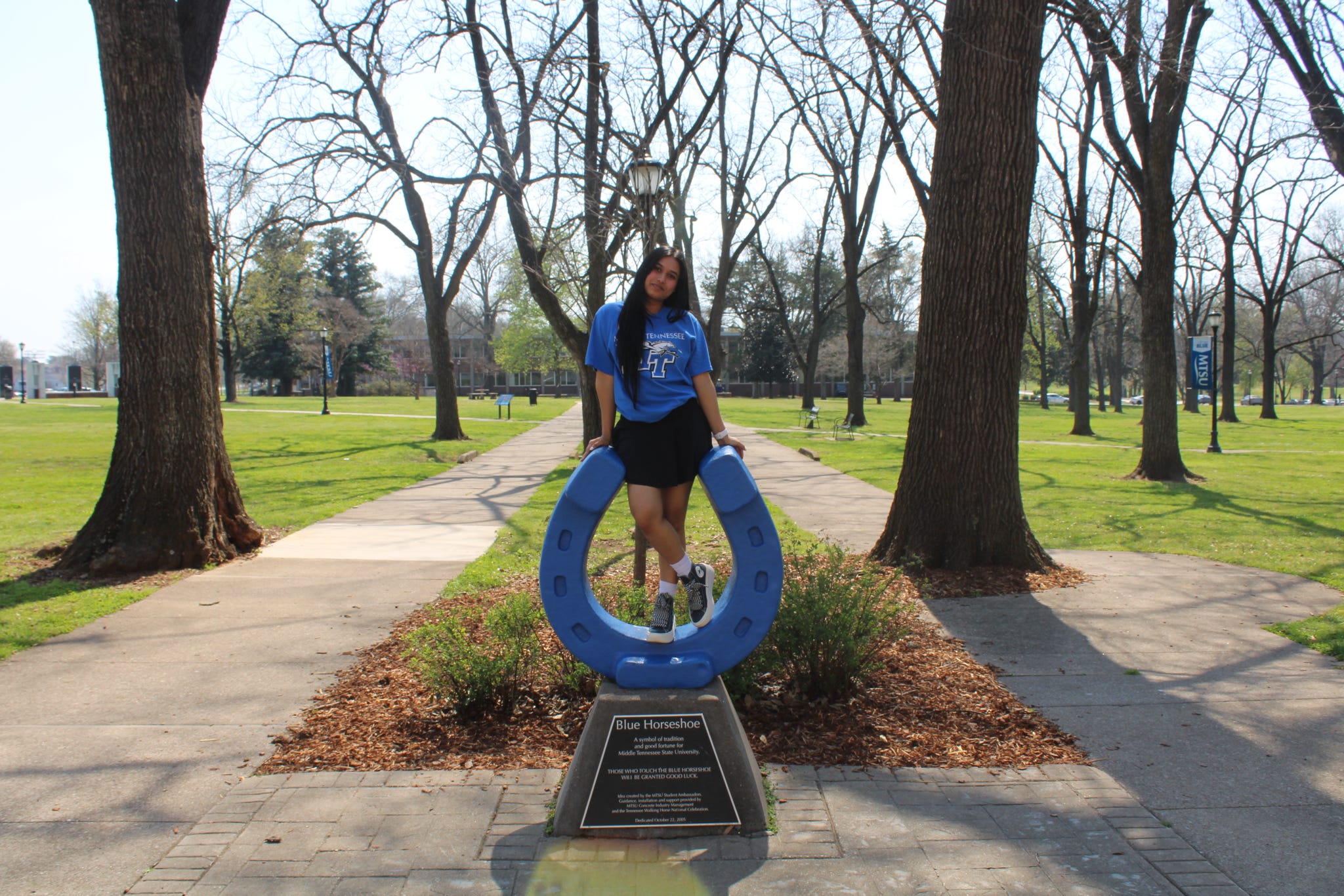 Photo of Hasni Liyanage standing on top of the blue horseshoe in Walnut Grove at MTSU.