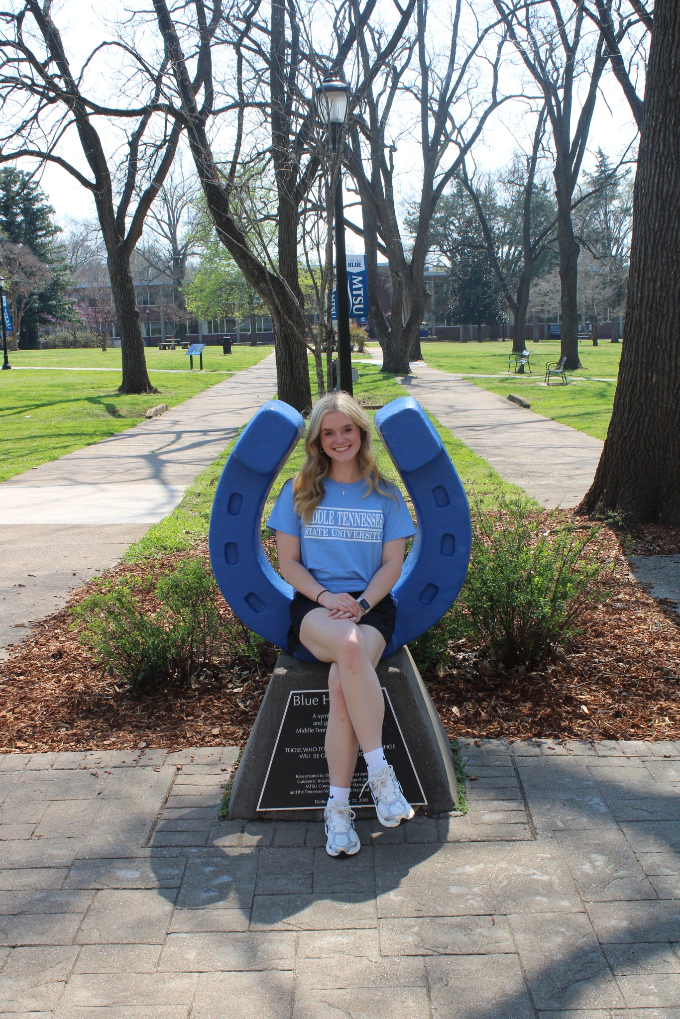 Photo of Jenna Wooten sitting on the blue horseshoe in Walnut Grove at MTSU.