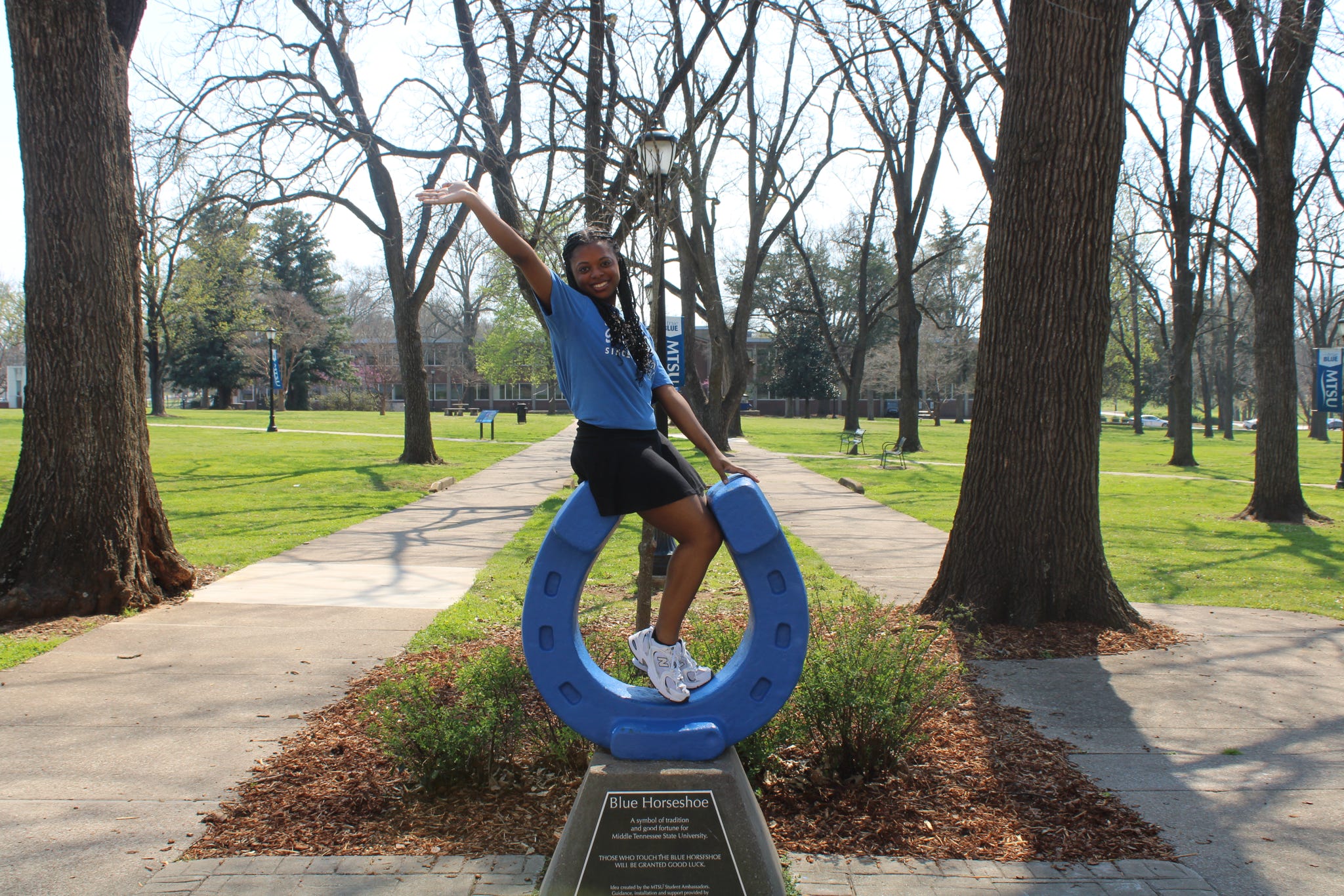 Photo of Kayla Hamilton standing on top of the blue horseshoe in Walnut Grove at MTSU.
