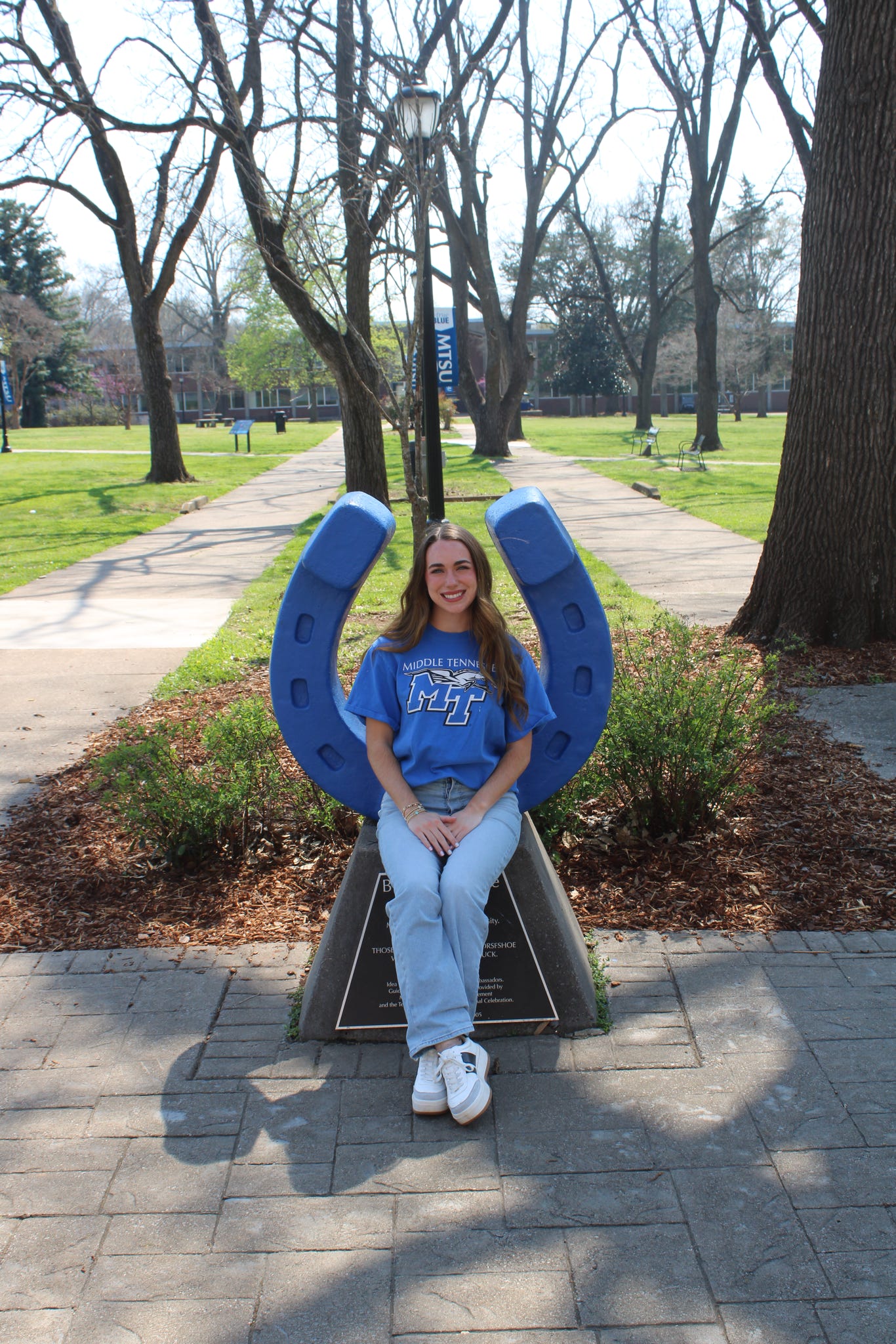 Photo of Maddie Sullivan sitting on the blue horseshoe in Walnut Grove at MTSU.