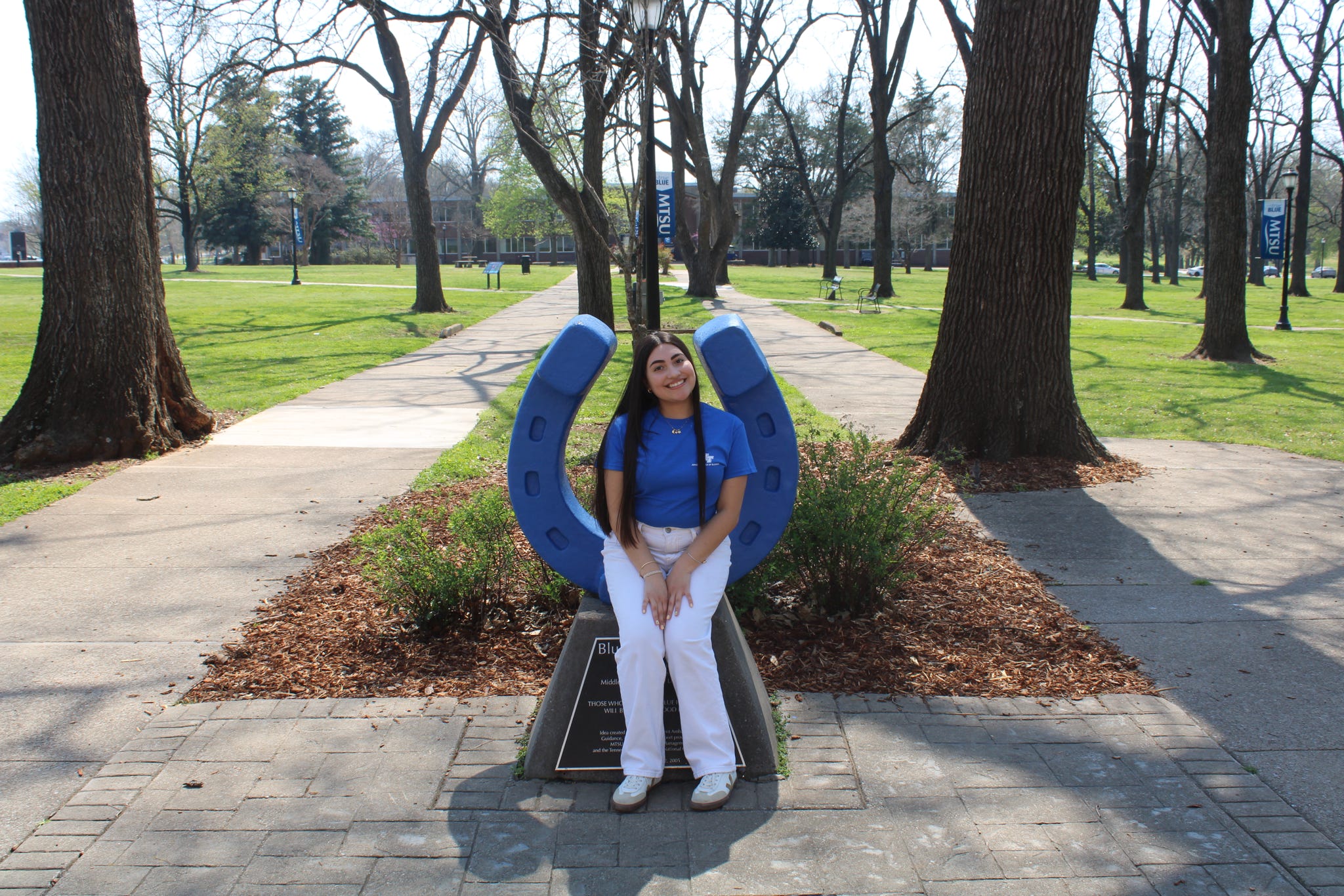 Photo of Mary Figuera sitting on the blue horseshoe in Walnut Grove at MTSU.