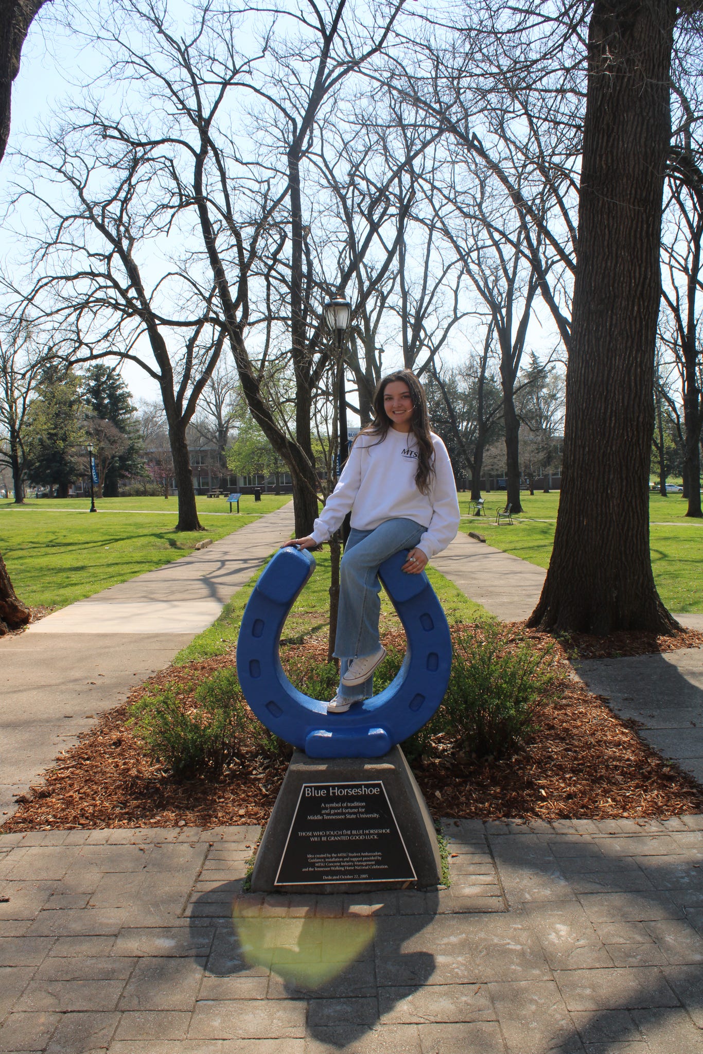 Photo of Milan DiMartino sitting on top of the blue horseshoe in Walnut Grove at MTSU.