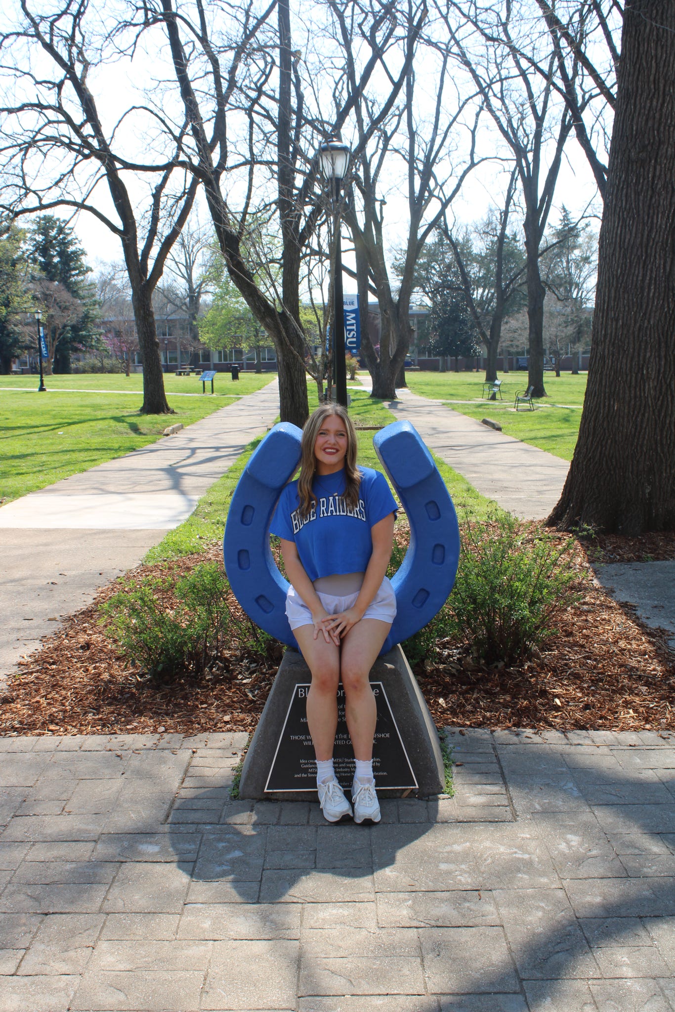 Photo of Raelin Tucker sitting on the blue horseshoe in Walnut Grove at MTSU.