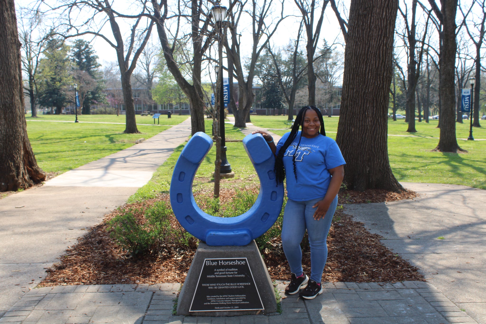 Photo of Reyonna Wesby standing beside the blue horseshoe in Walnut Grove at MTSU.