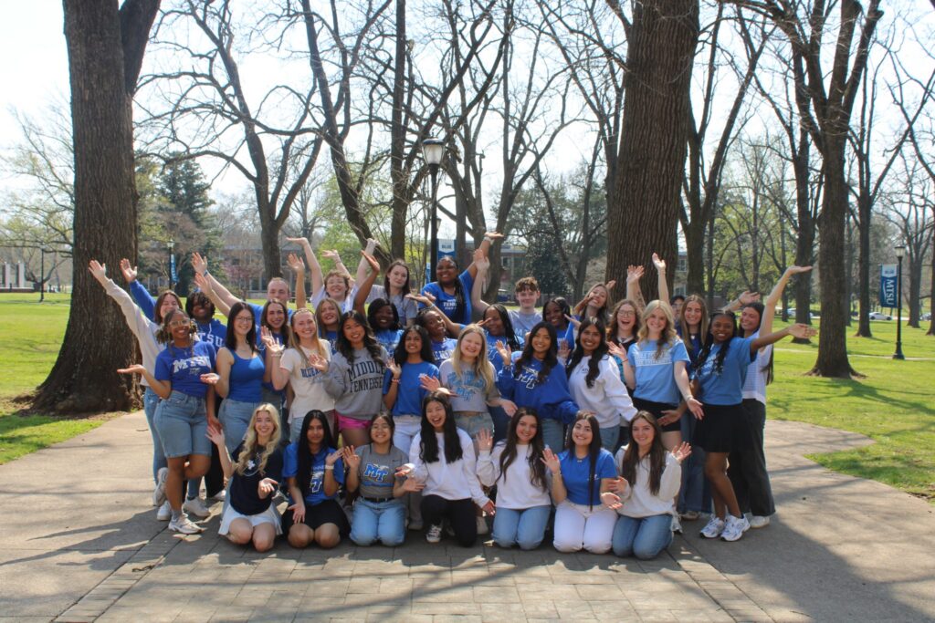 The 2026 cohort of Student Orientation Assistants posing together in front of the blue horseshoe in Walnut Grove at MTSU.