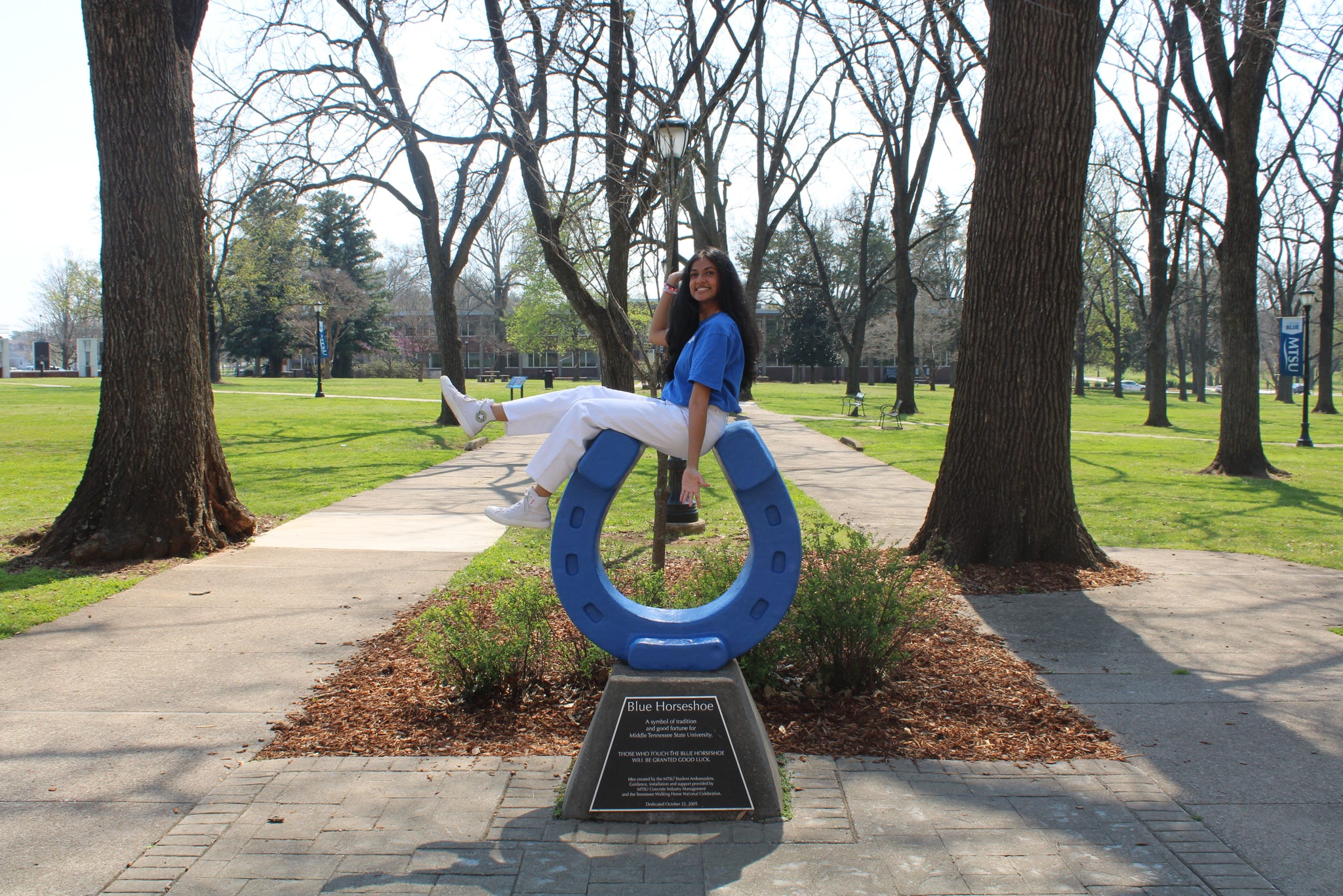 Photo of Vidhi Patel sitting on top of the blue horseshoe in Walnut Grove at MTSU.