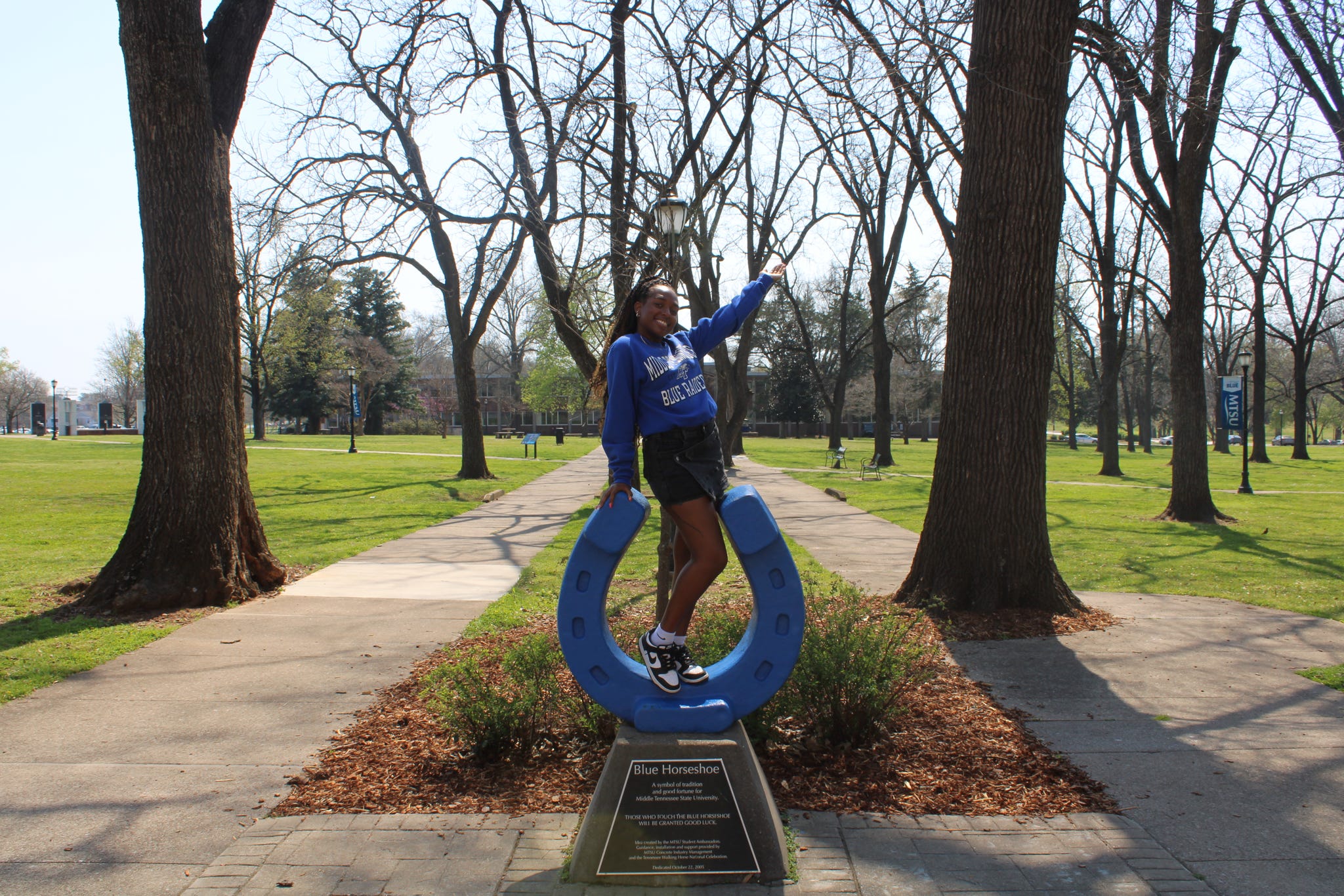 Photo of Zania Cole standing on top of the blue horseshoe in Walnut Grove at MTSU.