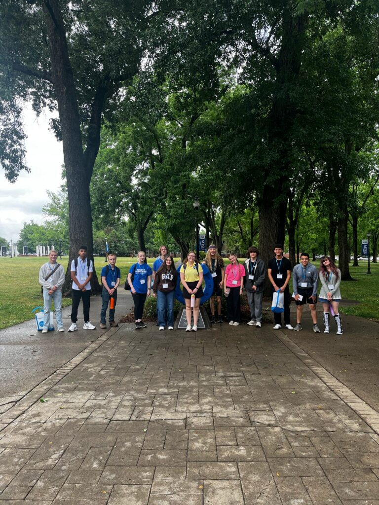 Students attending orientation posing for a photo at the blue horseshoe at MTSU with their Student Orientation Assistant.