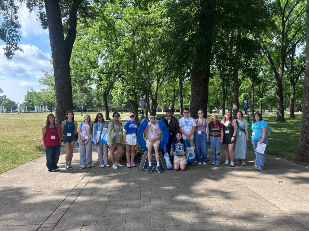 Students in Group 21 of orientation posing for a photo at the blue horseshoe at MTSU with their Student Orientation Assistant.