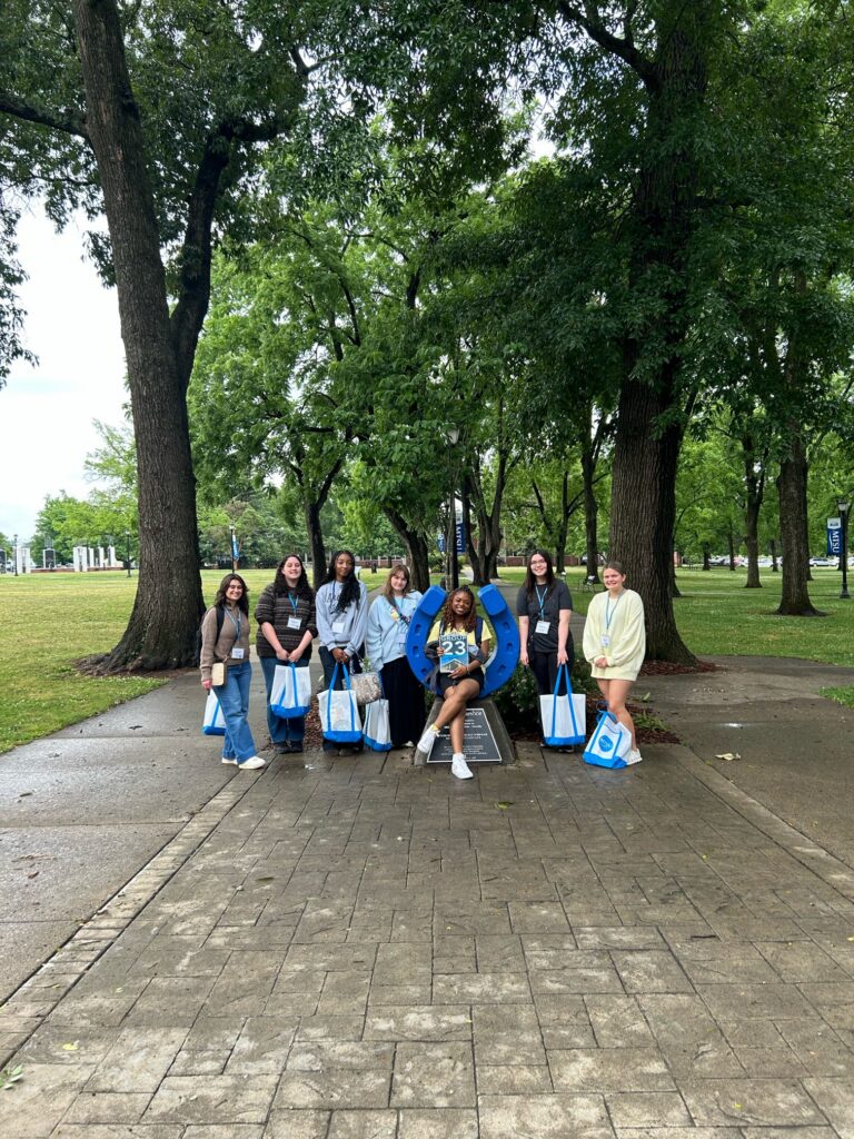Students in Group 23 of orientation posing for a photo at the blue horseshoe at MTSU with their Student Orientation Assistant.