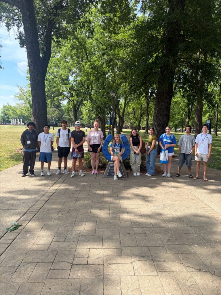 Students in Group 14 of orientation posing for a photo at the blue horseshoe at MTSU with their Student Orientation Assistant.