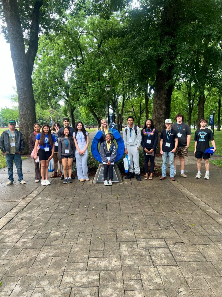 Students attending orientation posing for a photo at the blue horseshoe at MTSU with their Student Orientation Assistant.