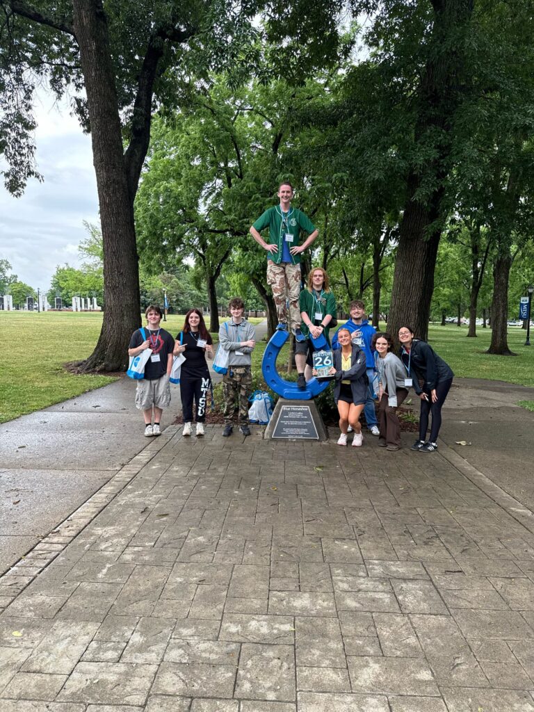 Students in Group 26 of orientation posing for a photo at the blue horseshoe at MTSU with their Student Orientation Assistant.