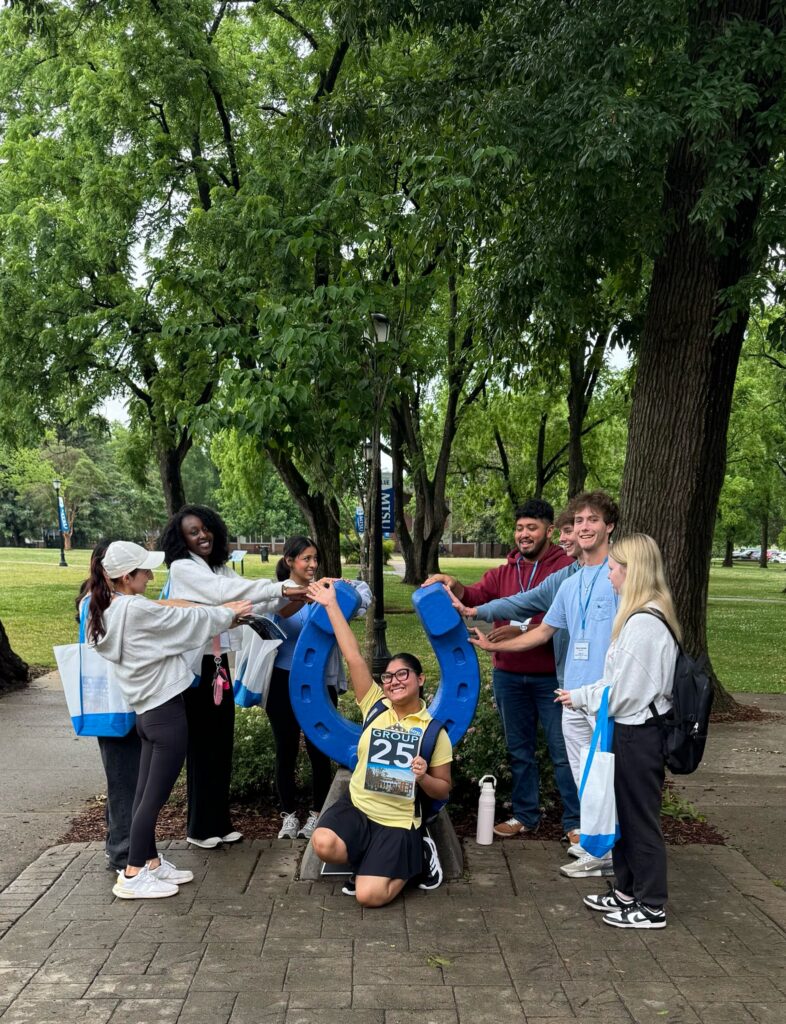 Students in Group 25 of orientation posing for a photo at the blue horseshoe at MTSU with their Student Orientation Assistant.