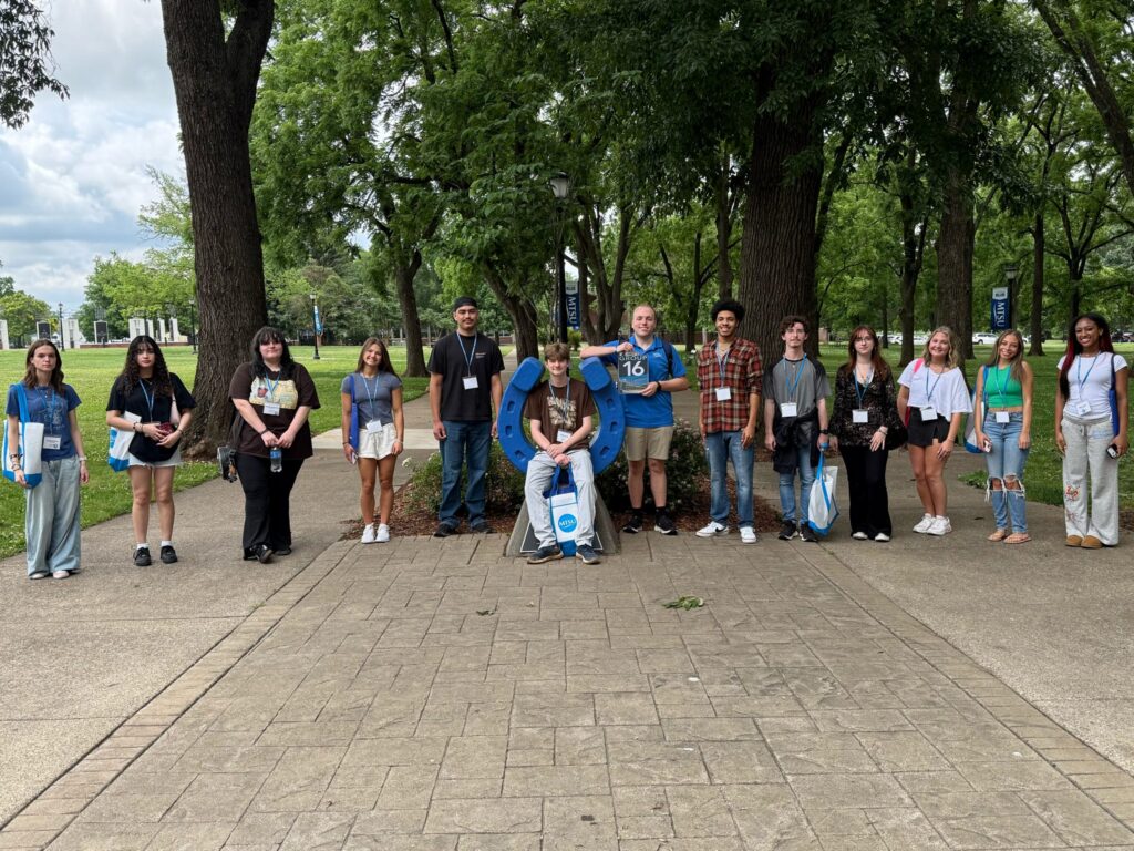 Students in Group 16 of orientation posing for a photo at the blue horseshoe at MTSU with their Student Orientation Assistant.