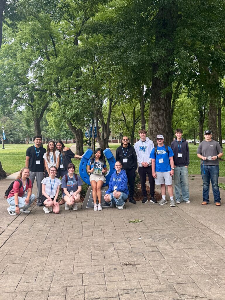 Students in Group 14 of orientation posing for a photo at the blue horseshoe at MTSU with their Student Orientation Assistant.