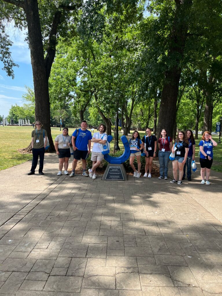 Students in Group 30 of orientation posing for a photo at the blue horseshoe at MTSU with their Student Orientation Assistant.